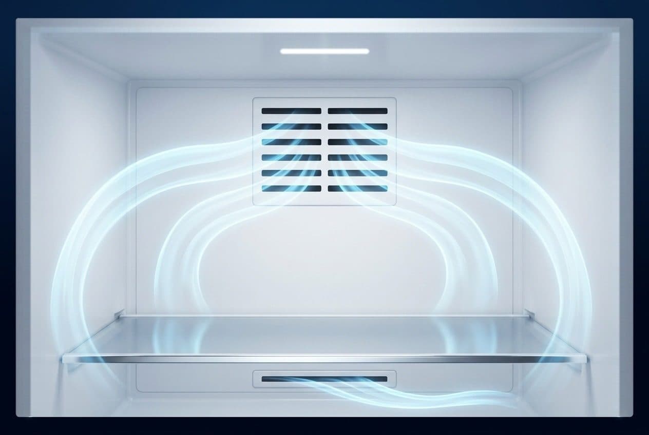 A frost-free fridge compartment seen straight on, with dry white walls, a small LED strip lamp in the ceiling, a louvred vent in the back wall, one glass shelf and a return slot, and translucent blue air ribbons curling from the vent over the shelf and back into the return, on a deep navy ground.